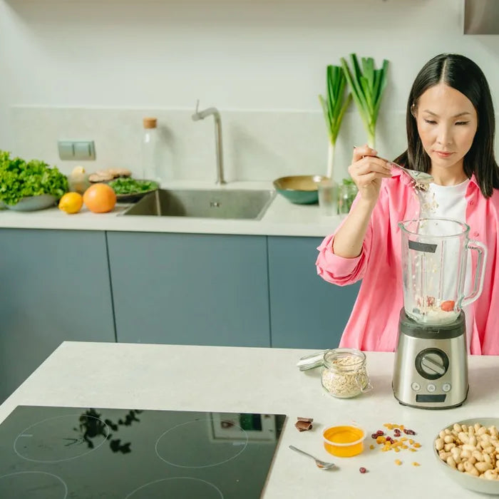 Woman making a fresh protein smoothie in her kitchen