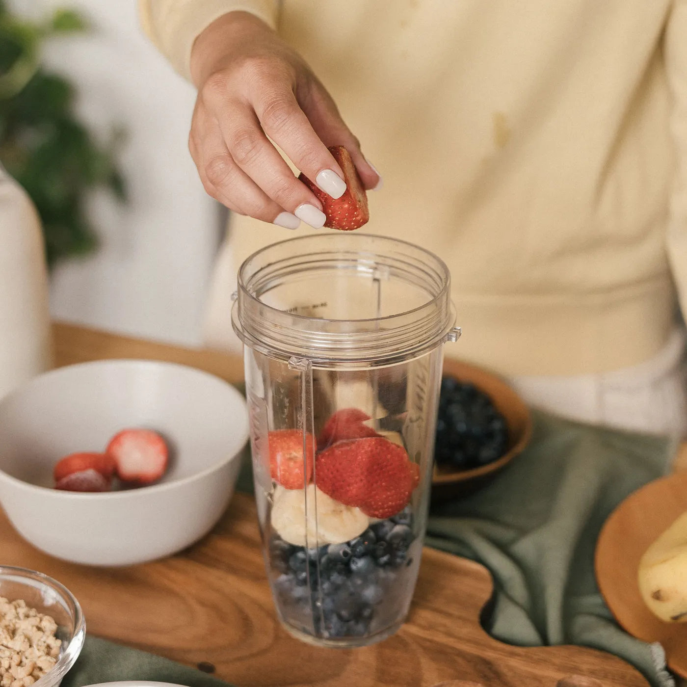 Adding fresh strawberries to a protein smoothie in the blender